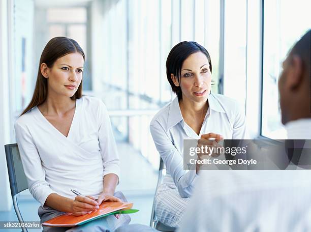 two businesswomen and a businessman discussing work in an office - maschio con gruppo di femmine foto e immagini stock