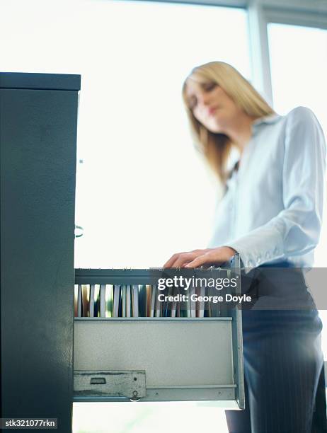 low angle view of a businesswoman searching through a filing cabinet - searching for something ストックフォトと画像