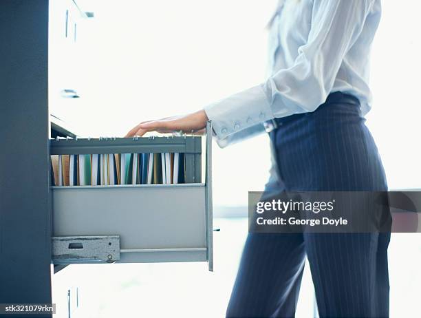 mid section view of a businesswoman sliding a drawer in an office - sliding door stockfoto's en -beelden