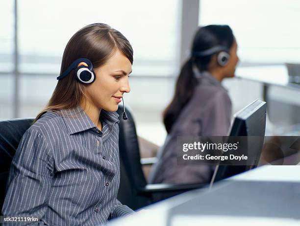 side profile of two businesswomen wearing headsets in an office - métier de la communication photos et images de collection