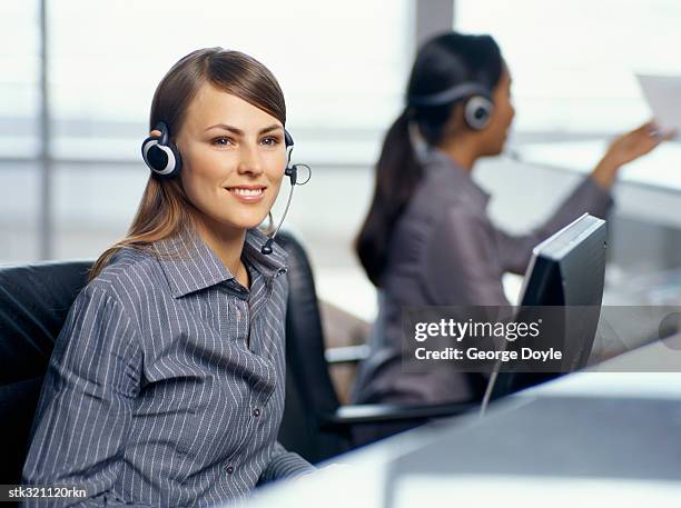 side profile of two businesswomen wearing headsets in an office - métier de la communication photos et images de collection