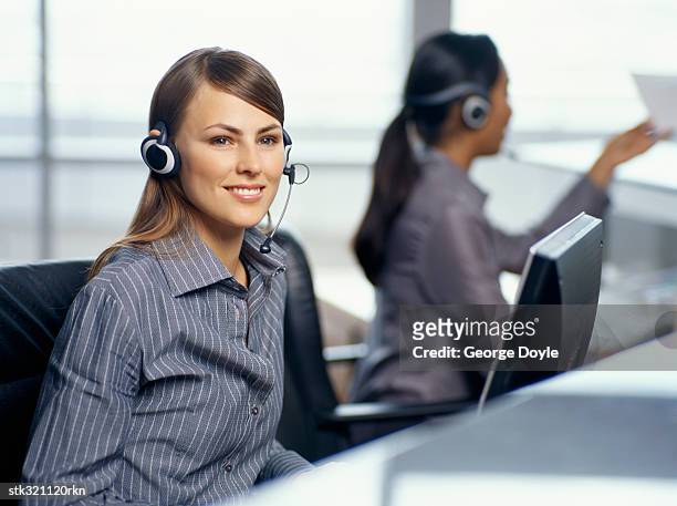 side profile of two businesswomen wearing headsets in an office - communication occupation stock pictures, royalty-free photos & images