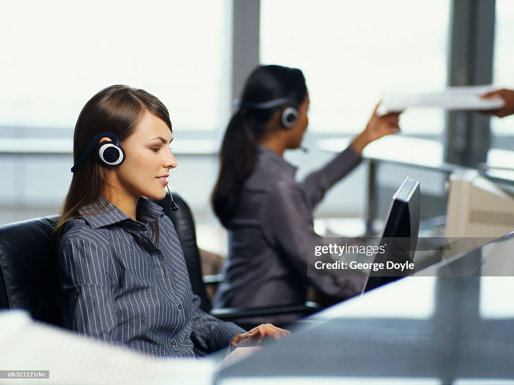 Side profile of two businesswomen wearing headset in an office