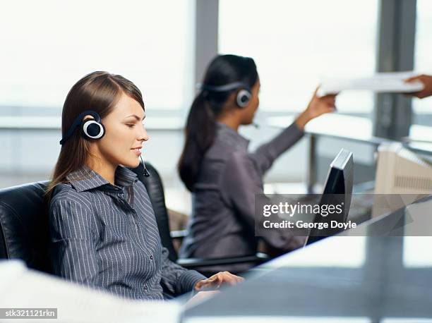 side profile of two businesswomen wearing headset in an office - communication occupation stock pictures, royalty-free photos & images