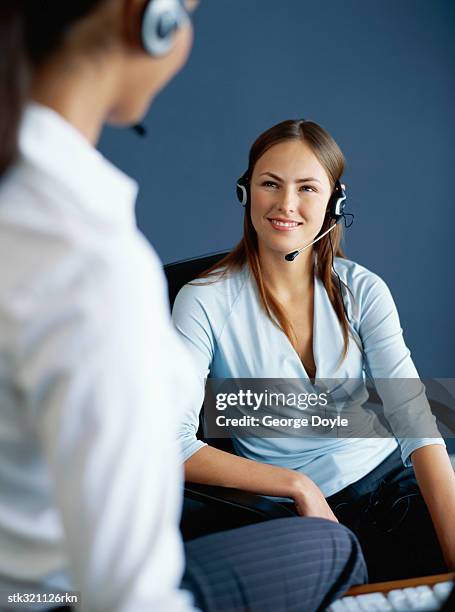 two businesswomen wearing headsets and talking in an office - communication occupation stock pictures, royalty-free photos & images