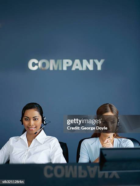 two businesswomen wearing headsets in an office - oficio de comunicaciones fotografías e imágenes de stock