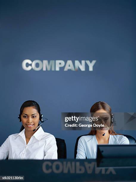 two businesswomen wearing headsets in an office - communication occupation stock pictures, royalty-free photos & images