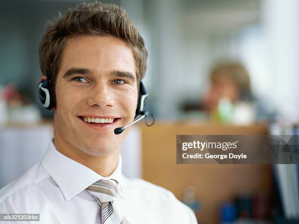 portrait of a businessman wearing a headset in an office - métier de la communication photos et images de collection