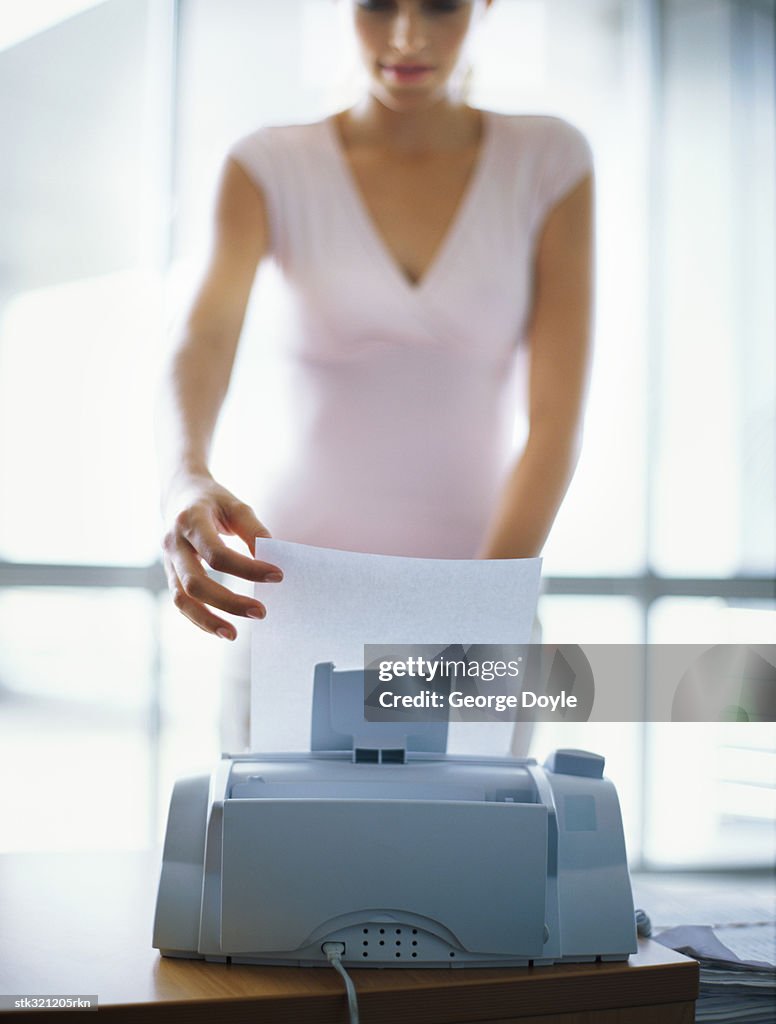 Businesswoman operating a fax machine in an office