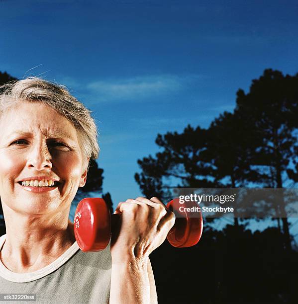 close-up of an elderly woman holding a dumbbell up to her chin - cross entwicklung stock-fotos und bilder