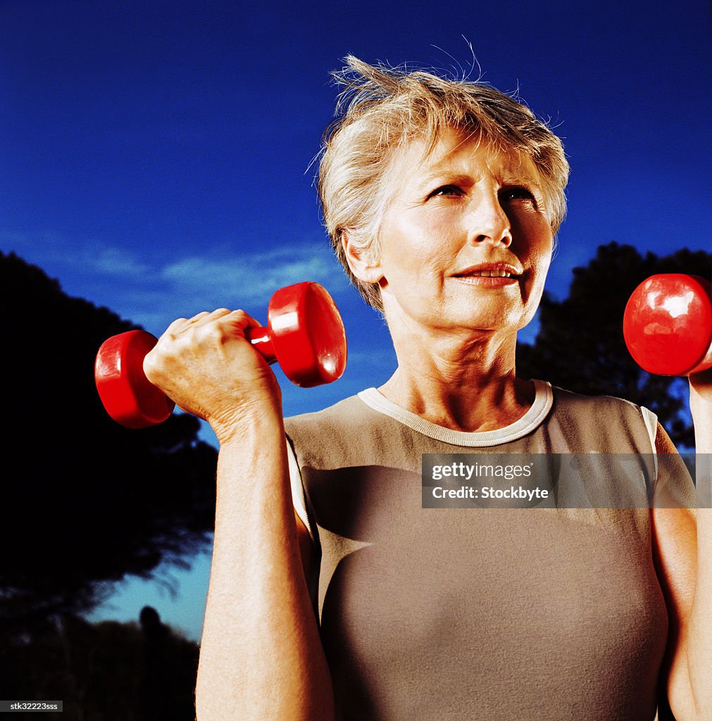 Close-up of an elderly woman holding up a set of dumbbells