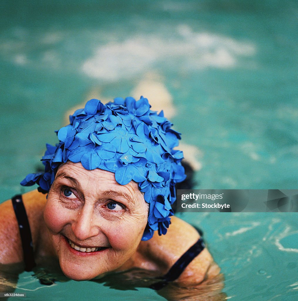 High angle view of an elderly woman in the swimming pool; smiling