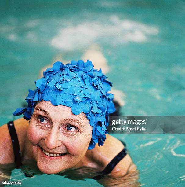 high angle view of an elderly woman in the swimming pool; smiling - touca de natação - fotografias e filmes do acervo