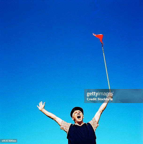 low angle view of a man shouting holding up a flag - cross-entwicklung stock-fotos und bilder