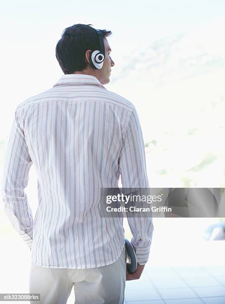 rear view of a young man wearing headphones and listening to music - audiogerät stock-fotos und bilder