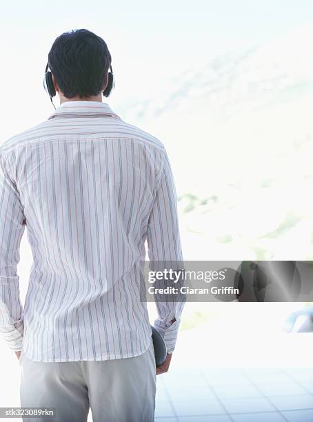 rear view of a young man wearing headphones and listening to music - audiogerät stock-fotos und bilder