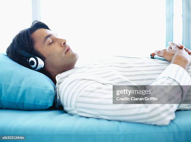 side profile of a mid adult man wearing headphones and sleeping - audiogerät stock-fotos und bilder