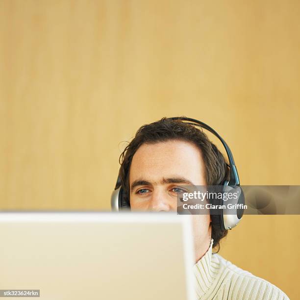 close-up of a businessman wearing headphones and using a computer - recreational equipment stock pictures, royalty-free photos & images