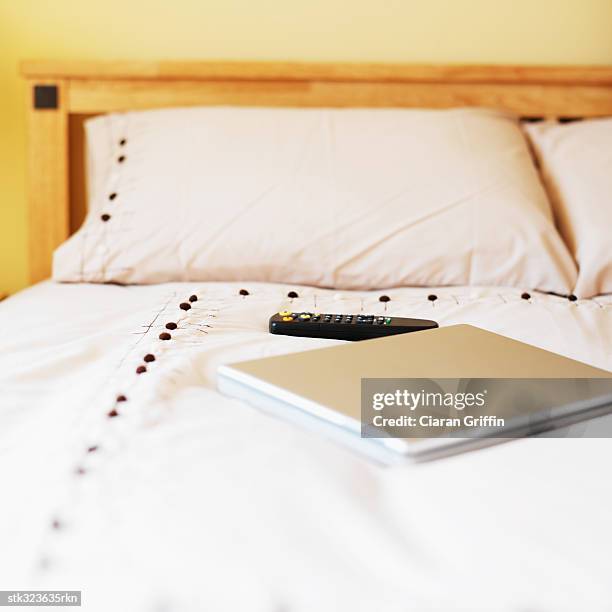 remote control and a laptop on a bed - control photos et images de collection