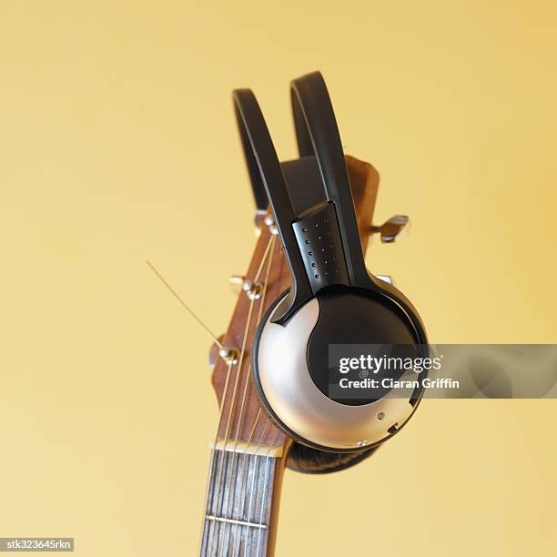 close-up of headphones hanging on top of a guitar - recreational equipment stock pictures, royalty-free photos & images