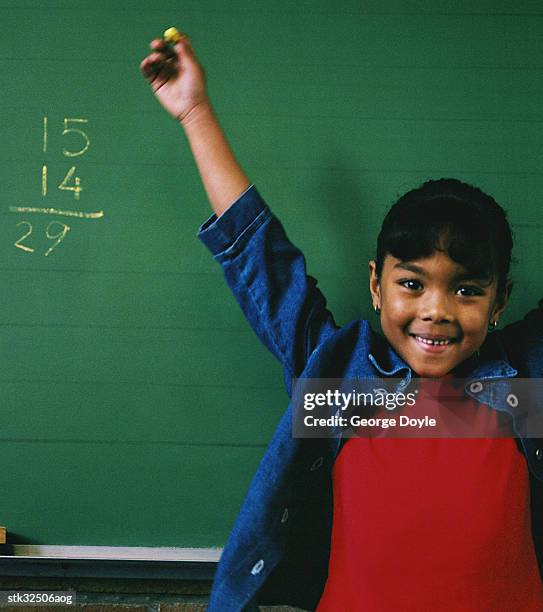 close-up of a girl (6-8) standing in front of a chalkboard with arms raised; smiling - människolem bildbanksfoton och bilder