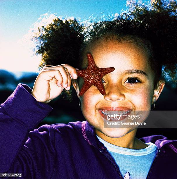 close-up of a girl (6-8) holding up a starfish to her eye - unveiling of life size statue of andrea bocelli at keep memory alive event center stockfoto's en -beelden
