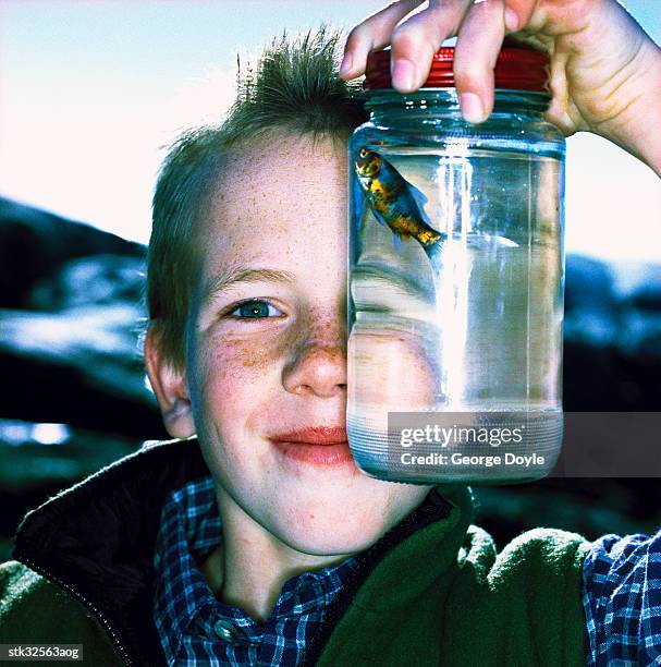 close-up of a boy (8-10) holding up a fish in a jar - unveiling of life size statue of andrea bocelli at keep memory alive event center stockfoto's en -beelden