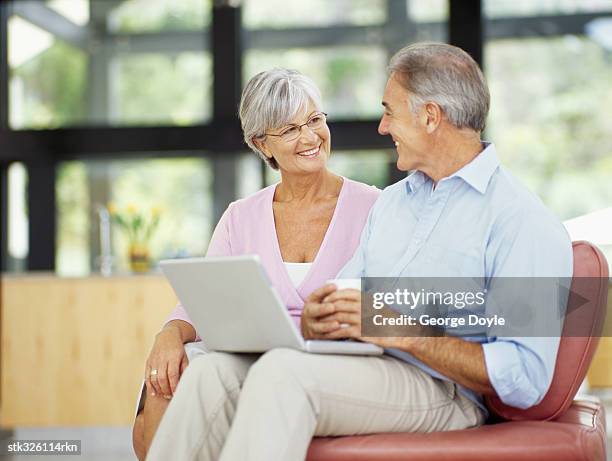 mature couple sitting together with a laptop - hand on knee stock pictures, royalty-free photos & images