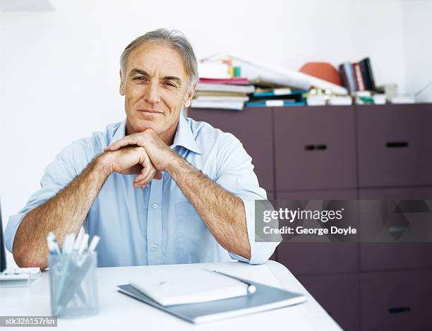 portrait of a mature man sitting with his hand on his chin - writing instrument stock pictures, royalty-free photos & images