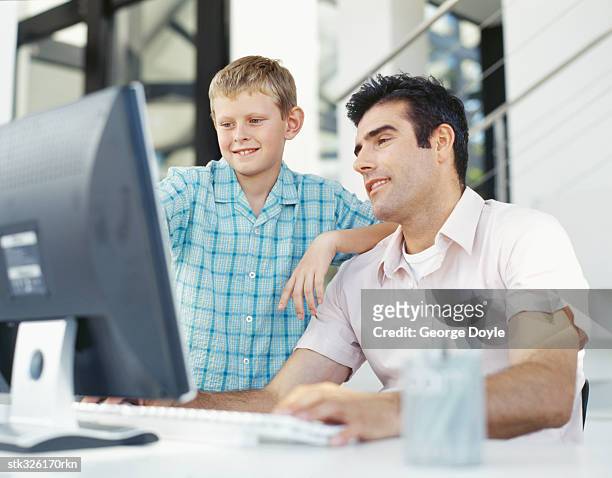 father and his son using a computer - writing instrument stock pictures, royalty-free photos & images