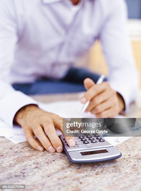 mid section view of a man using a calculator - instrumento de contar fotografías e imágenes de stock