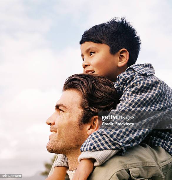 a young boy (4-6) sitting on his father's shoulders - genderblend stock pictures, royalty-free photos & images