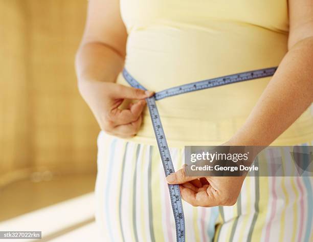 mid section view of a woman measuring her waist - inch stock pictures, royalty-free photos & images