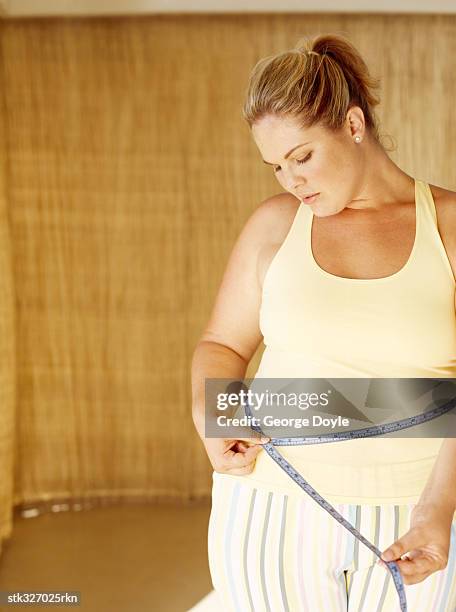 mid adult woman measuring her waist - inch stock pictures, royalty-free photos & images