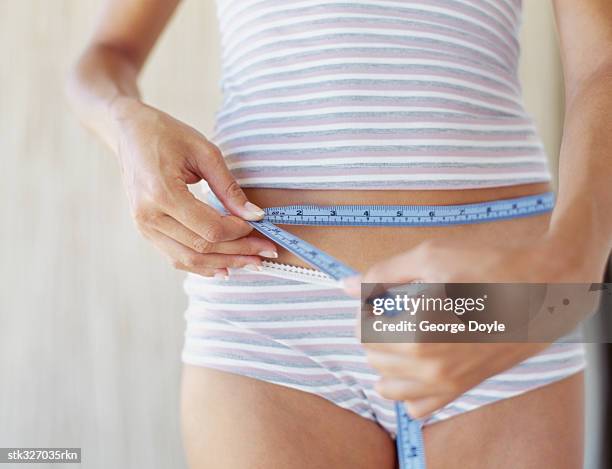 mid section view of a woman measuring her waist - inch stock pictures, royalty-free photos & images
