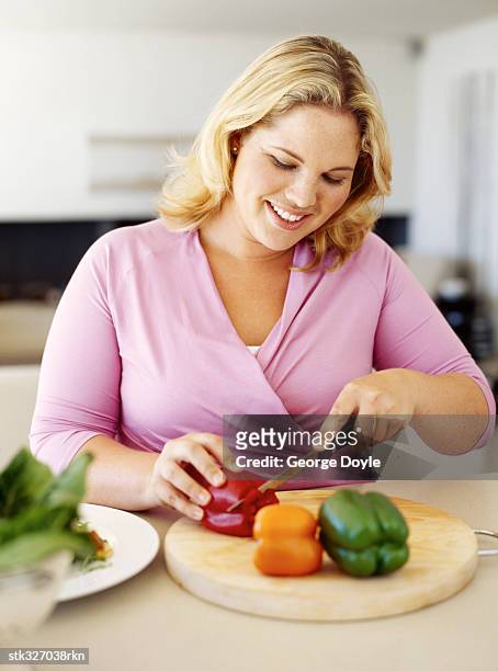 mid adult woman cutting vegetables - oranje paprika stockfoto's en -beelden
