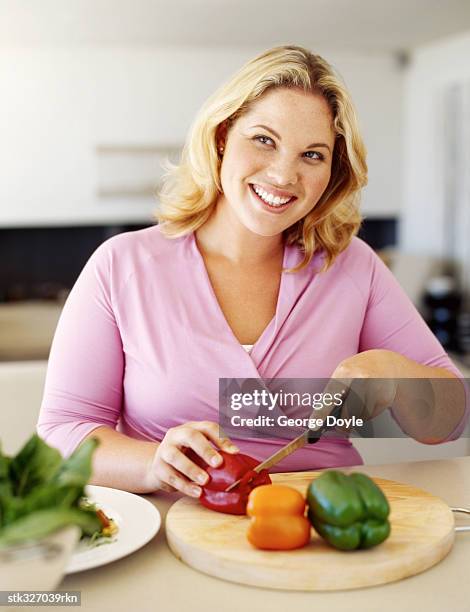 mid adult woman cutting vegetables - oranje paprika stockfoto's en -beelden