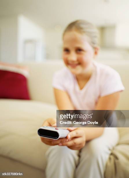 girl sitting on a couch and using a remote control - control photos et images de collection