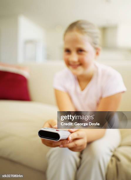 girl sitting on a couch and using a remote control - recreational equipment stock pictures, royalty-free photos & images