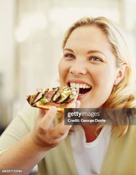 mid adult woman eating a slice of pizza - slice stock pictures, royalty-free photos & images