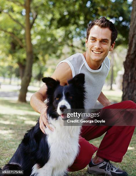 young man sitting with his dog in a park - gray eyes stock-fotos und bilder