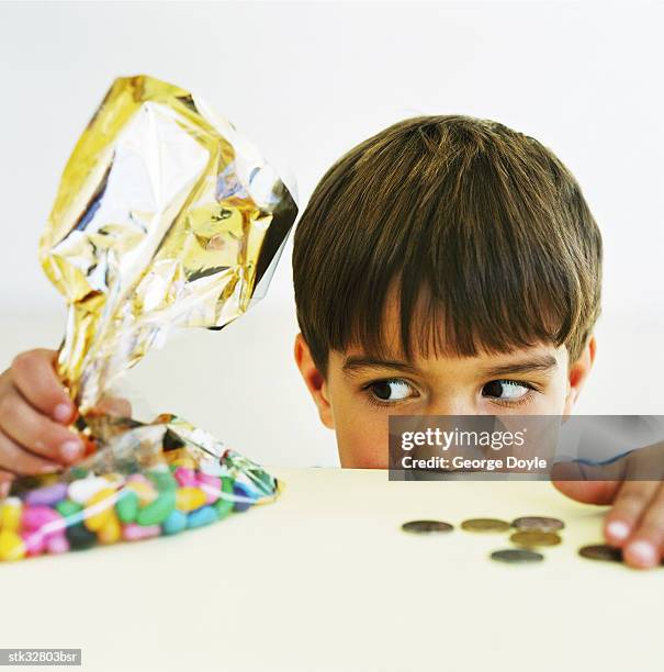 view of a young boy (8-10) standing behind a counter with a bag of candy and money - retail equipment stock pictures, royalty-free photos & images