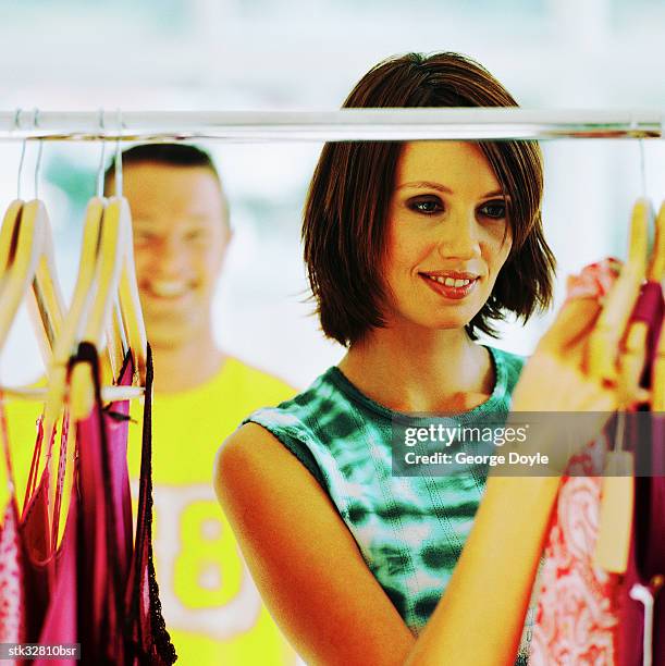 view of a young woman choosing an outfit from a clothes rack with a young man in background - retail of amorepacific corp brands as south koreas biggest cosmetics makers revamps product lineup stockfoto's en -beelden