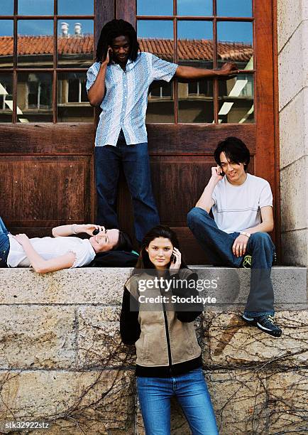 view of four students sitting outside a door and talking on their mobile phones - the academy of television arts sciences and sag aftra celebrate the 65th primetime emmy award nominees stockfoto's en -beelden