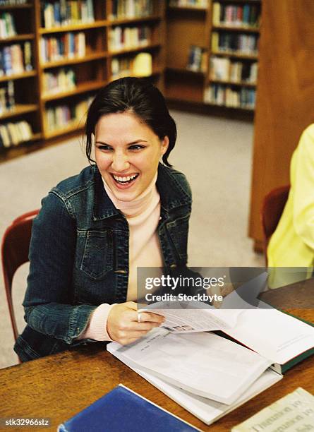 view of a young woman sitting in a library with a book and laughing - academy of motion picture arts sciences oscar night celebration stockfoto's en -beelden