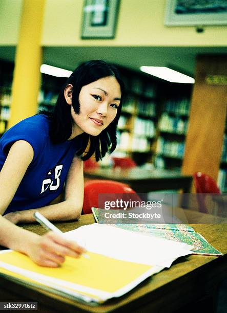 portrait of a young woman in a library writing - writing instrument stock pictures, royalty-free photos & images