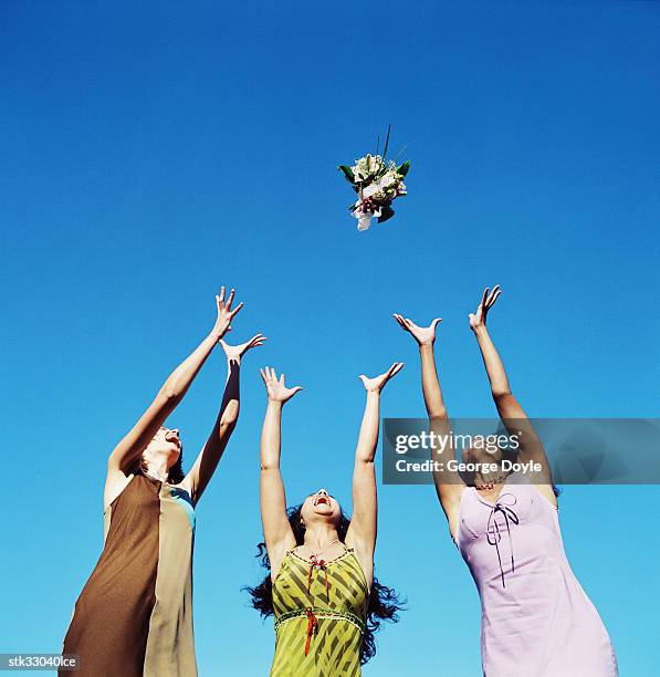 low angle view of three women leaping for the bride's bouquet - människolem bildbanksfoton och bilder