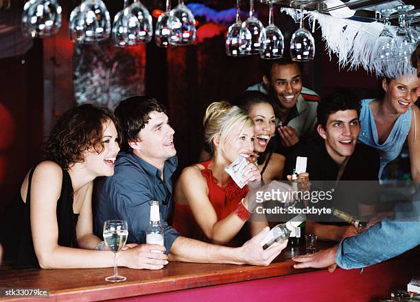 view of men and women jostling at a bar counter - bar ストックフォトと画像