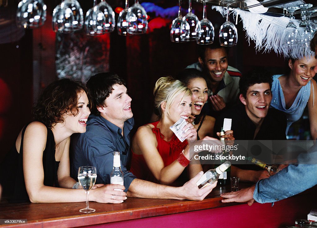 View of men and women jostling at a bar counter