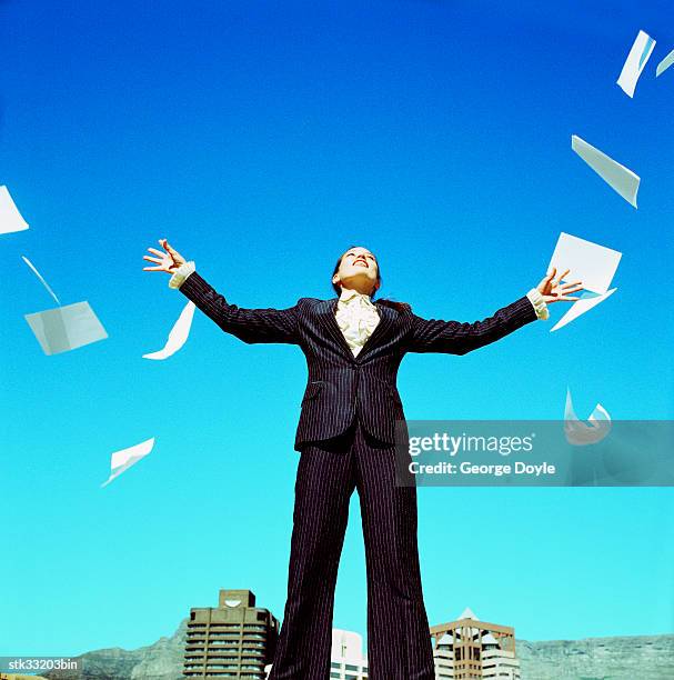 low angle view of a businesswoman throwing sheets of paper in the air - cross-entwicklung stock-fotos und bilder